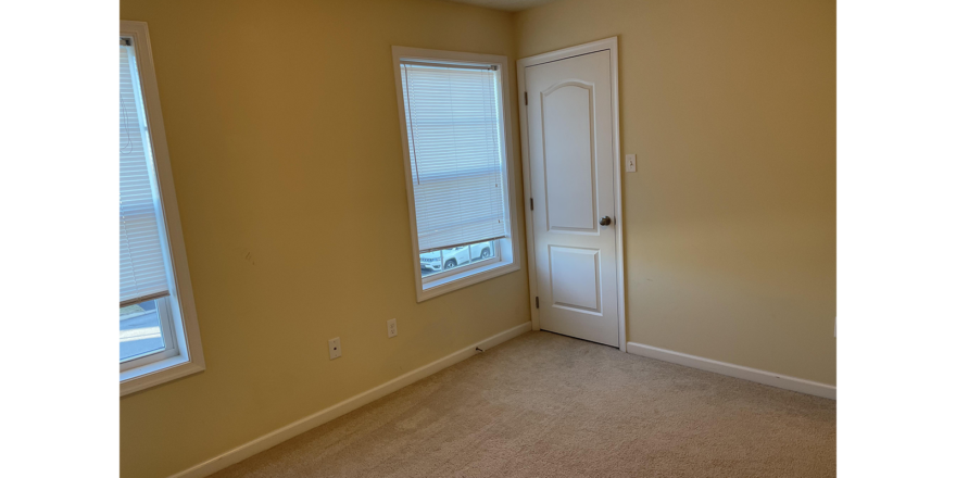 an empty room with two windows and a door