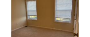 an empty room with two windows and carpet