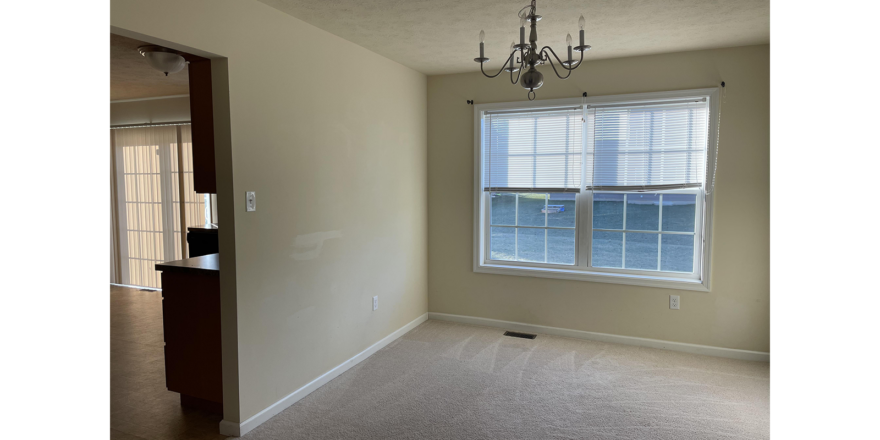 an empty room with a chandelier and window