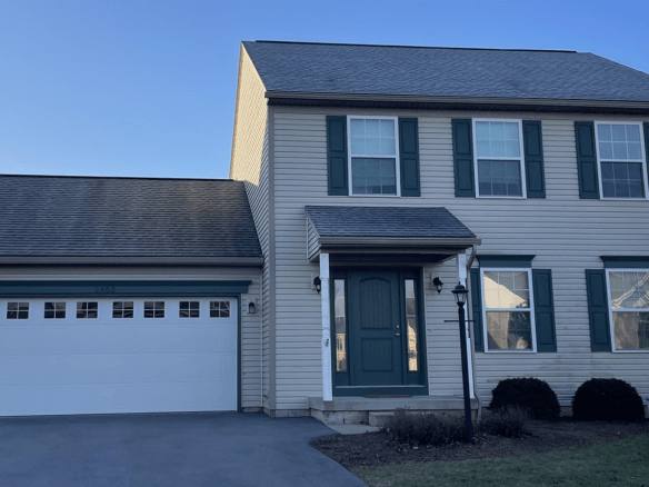 a two story house with green shutters and a white garage