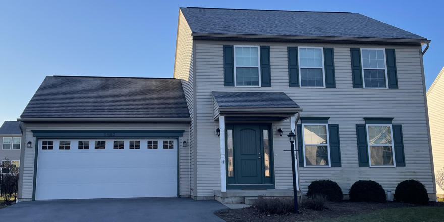 a two story house with green shutters and a white garage