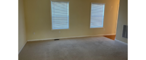 an empty room with two windows and carpet