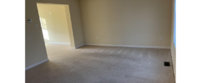 an empty living room with carpet and door