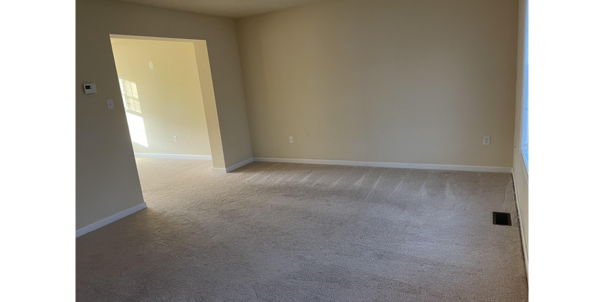 an empty living room with carpet and door