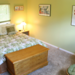Bedroom with green walls, queen-sized bed, two end tables, and a lounge chair