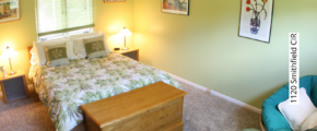 Bedroom with green walls, queen-sized bed, two end tables, and a lounge chair