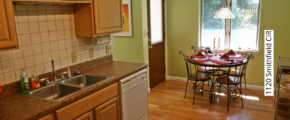 Kitchen with tan cabinets, white appliances, white tile backsplash, and small kitchen table