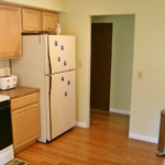Kitchen with white and black appliances, and light tan cabinets.