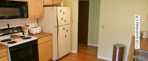 Kitchen with white and black appliances, and light tan cabinets.