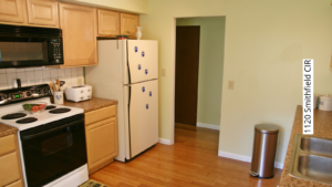 Kitchen with white and black appliances, and light tan cabinets.