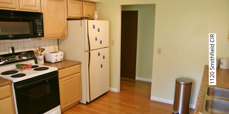 Kitchen with white and black appliances, and light tan cabinets.