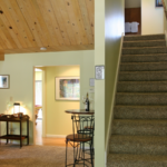 Carpeted stairs leading to the second floor. Bar-height table with two chairs and a bar cart.
