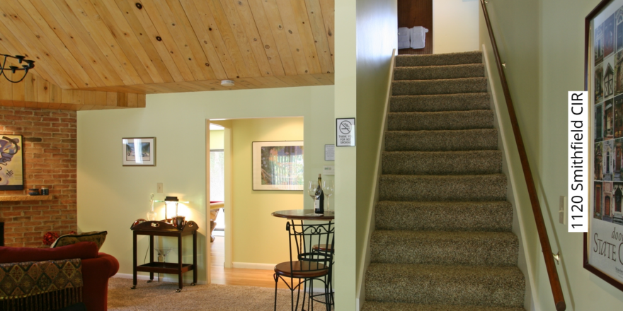 Carpeted stairs leading to the second floor. Bar-height table with two chairs and a bar cart.