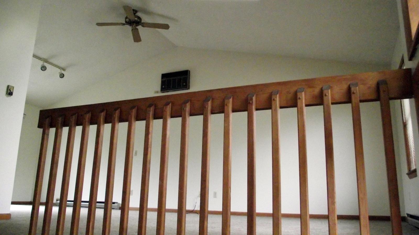 Wooden railing divides rooms with vaulted ceiling