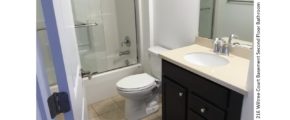 Bathroom with vanity, mirror, toilet, and tub/shower combo with sliding glass door