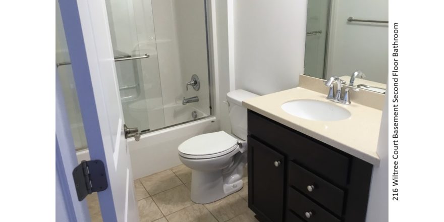 Bathroom with vanity, mirror, toilet, and tub/shower combo with sliding glass door