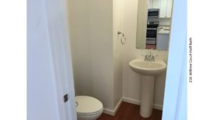 Half-bathroom with toilet, pedestal sink, and mirror