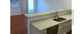Kitchen with white countertops and cabinets, stainless steel dishwasher and sink and breakfast bar