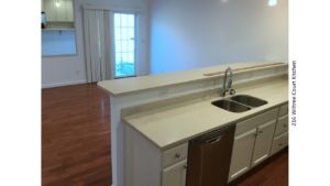 Kitchen with white countertops and cabinets, stainless steel dishwasher and sink and breakfast bar