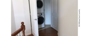 Laundry closet with white, stacked washer and dryer