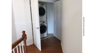 Laundry closet with white, stacked washer and dryer