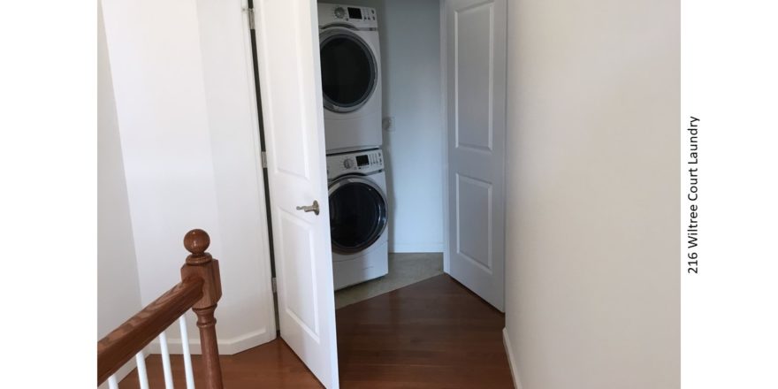 Laundry closet with white, stacked washer and dryer
