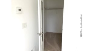 Carpeted walk in closet with white wire shelving and clothes rods