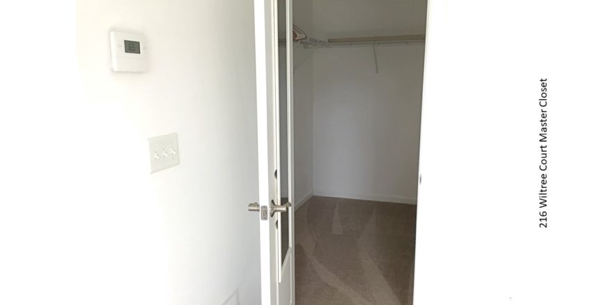 Carpeted walk in closet with white wire shelving and clothes rods