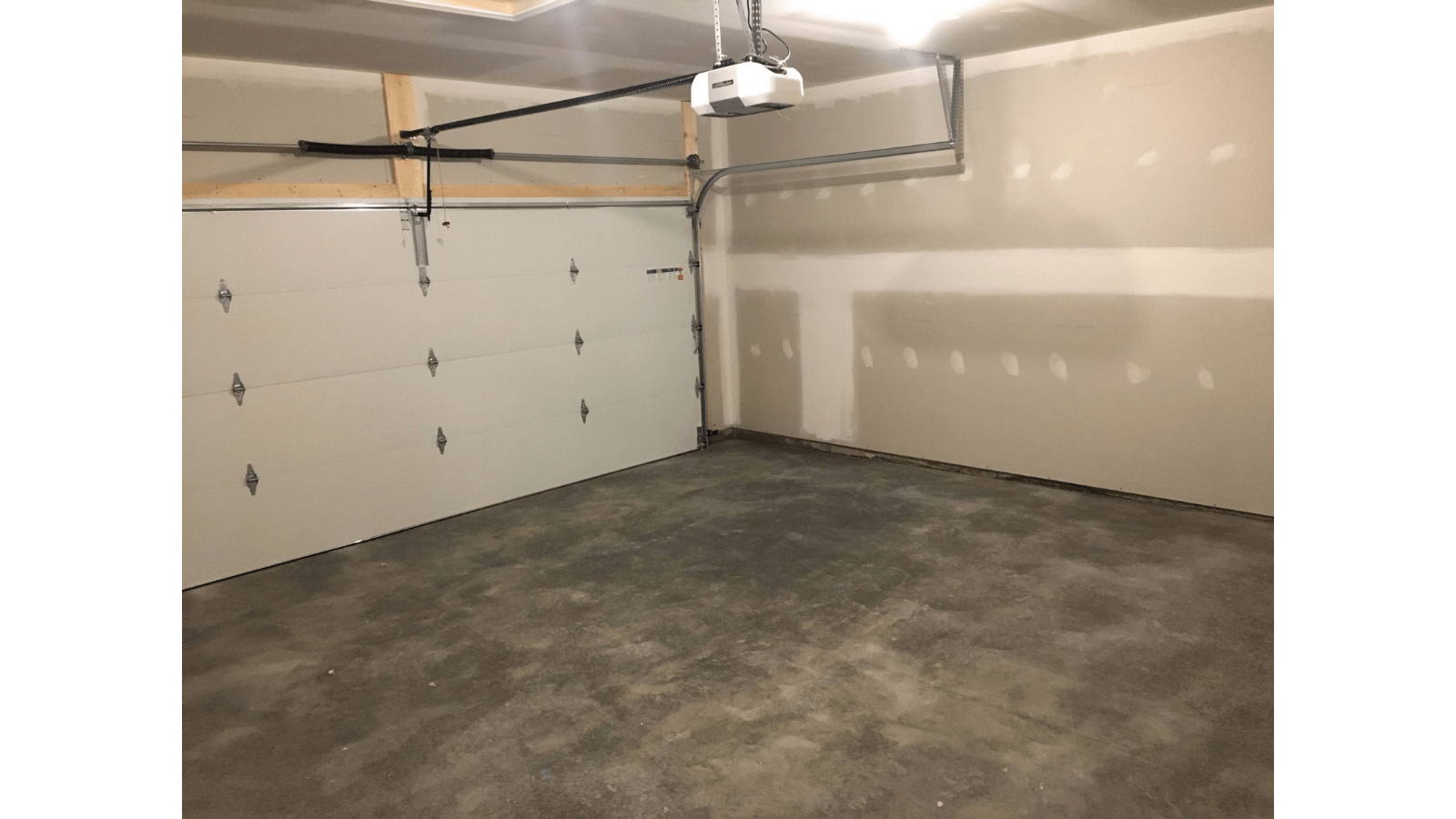 Empty garage with white door and concrete floor