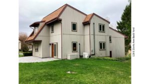 Rear exterior with patio and lawn. House has vertical, tan siding.