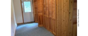 Carpeted basement with wood storage closets and exterior door.