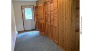 Carpeted basement with wood storage closets and exterior door.