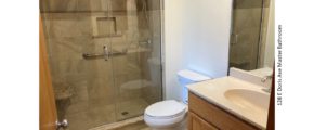 Bathroom with tile shower with glass door and seat, toilet, and vanity with mirror