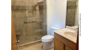 Bathroom with tile shower with glass door and seat, toilet, and vanity with mirror