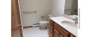 Bathroom with tile floor, toilet and large vanity and mirror