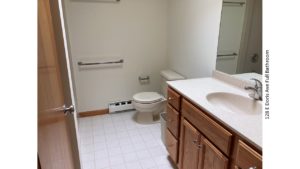 Bathroom with tile floor, toilet and large vanity and mirror