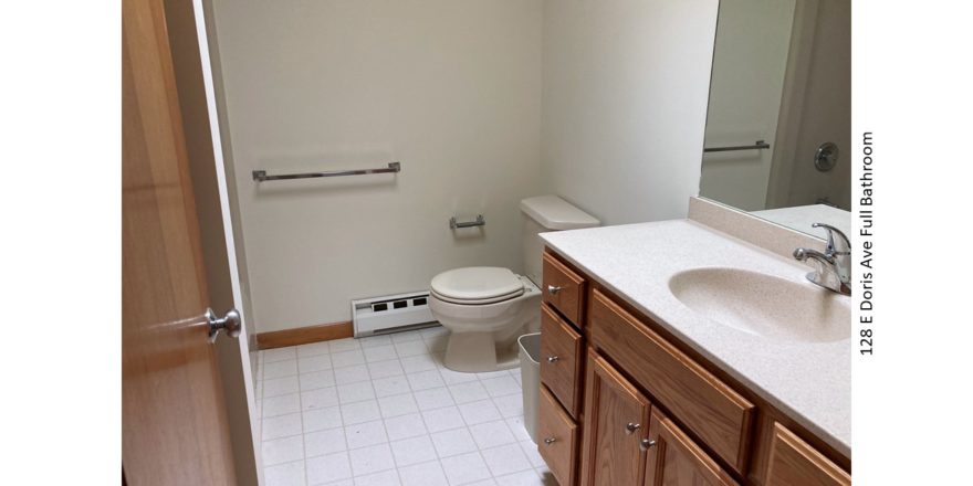 Bathroom with tile floor, toilet and large vanity and mirror