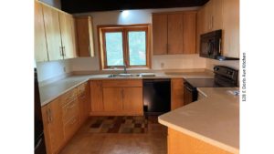 Kitchen with black appliances, parkay flooring, and light wood cabinets