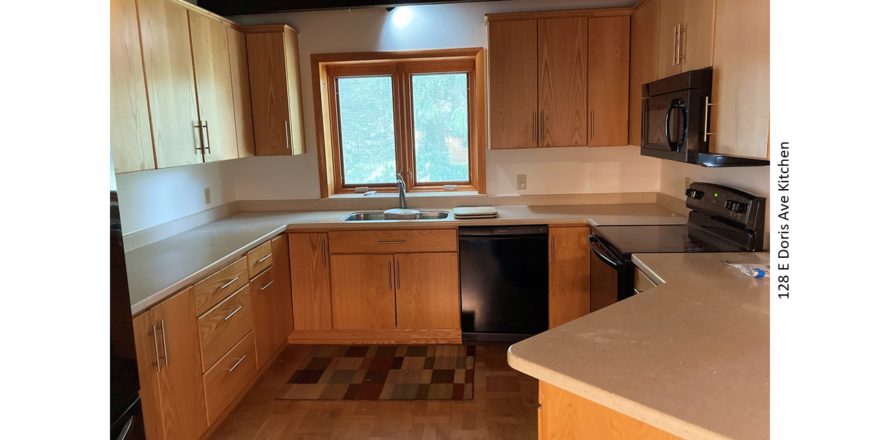 Kitchen with black appliances, parkay flooring, and light wood cabinets