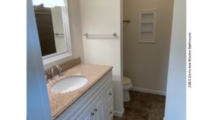 Bathroom with vanity, mirror, and toilet behind a partition wall