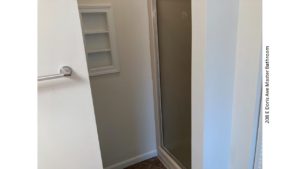 Bathroom shower stall with glass door and built-in shelf on the outside