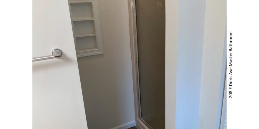 Bathroom shower stall with glass door and built-in shelf on the outside