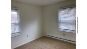 Unfurnished, carpeted bedroom with two windows