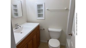 Bathroom with shower/tub combo, toilet, vanity and built-in shelves.