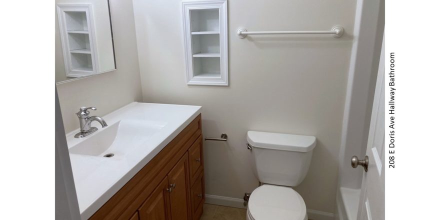 Bathroom with shower/tub combo, toilet, vanity and built-in shelves.