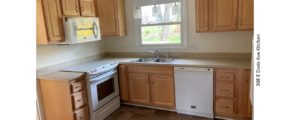 Kitchen with double sink, white appliances, and light wood cabinets