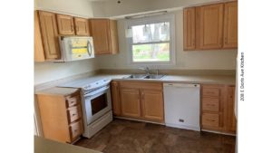 Kitchen with double sink, white appliances, and light wood cabinets