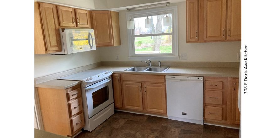 Kitchen with double sink, white appliances, and light wood cabinets