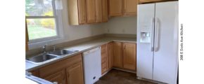 Kitchen with double sink, white appliances, and light wood cabinets