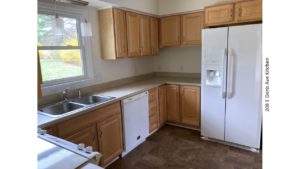 Kitchen with double sink, white appliances, and light wood cabinets